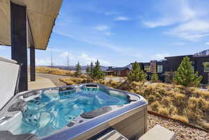 View of pool featuring a hot tub, patio surround, and a mountain view