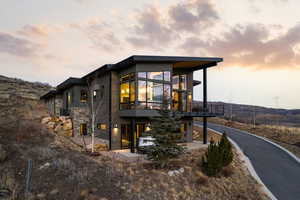 View of front of home with stone siding, a patio area, and a balcony