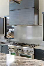 Kitchen featuring range with two ovens, gray cabinetry, and light stone counters