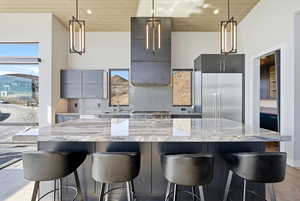 Kitchen featuring light wood-style flooring, a kitchen breakfast bar, a high wood ceiling, modern cabinets, and decorative light fixtures