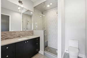 Full bathroom with a shower stall, vanity, backsplash, and recessed lighting