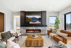 Living area with a stone fireplace, wood finished floors, and recessed lighting
