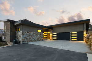 Modern home featuring stone siding, concrete driveway, and a garage