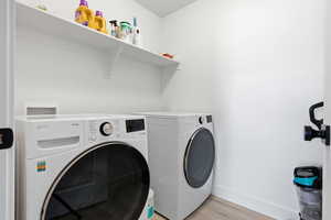 Laundry room with light wood finished floors and washing machine and dryer