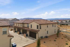 Rear view of house featuring a garage, stucco siding, a residential view, driveway, and a tiled roof