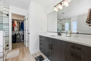 Bathroom featuring vanity, a spacious closet, a shower stall, and light wood-type flooring