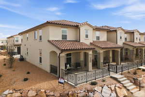 Rear view of house featuring stucco siding, a patio, a tiled roof, and a residential view