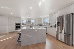 Kitchen with modern cabinets, stainless steel appliances, a kitchen breakfast bar, a center island, and recessed lighting
