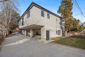 Rear view of house featuring stucco siding, an attached garage, and concrete driveway