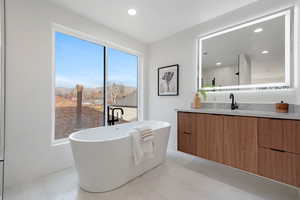 Full bathroom featuring vanity, a freestanding tub, a mountain view, recessed lighting, and light tile patterned floors