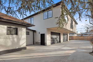 Rear view of house with an attached garage, stucco siding, and driveway