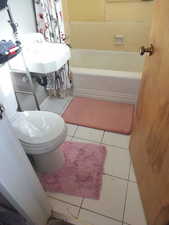 Bathroom with light tile patterned flooring and shower / tub combo