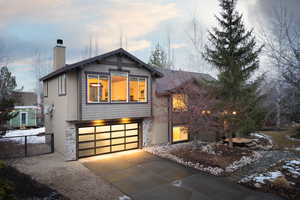 View of front of home featuring stone siding, an attached garage, a gate, and a chimney