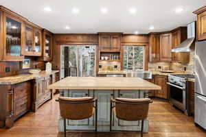 Kitchen with light stone counters, stainless steel appliances, recessed lighting, a breakfast bar, and dark wood-style flooring