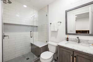 Bathroom with a stall shower, vanity, and recessed lighting