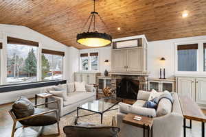 Living area featuring plenty of natural light, a stone fireplace, a vaulted wood ceiling, and recessed lighting