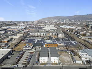 Aerial view of property and surrounding area featuring industrial structures and a mountainous background