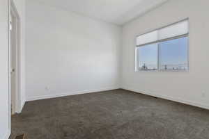 Unfurnished bedroom with dark carpet and baseboards
