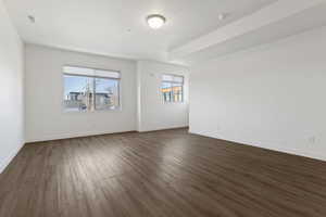Unfurnished room featuring dark wood-style flooring and baseboards