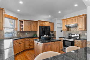 Kitchen featuring stainless steel appliances, a kitchen island, open shelves, light wood finished floors, and wood finish cabinetry