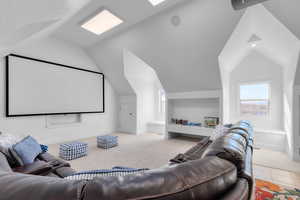 Home theater room featuring lofted ceiling and light carpet