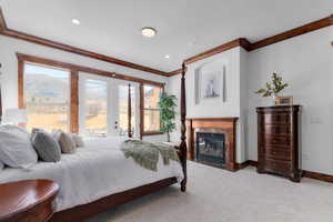 Carpeted bedroom with ornamental molding, a high end fireplace, access to exterior, french doors, and recessed lighting