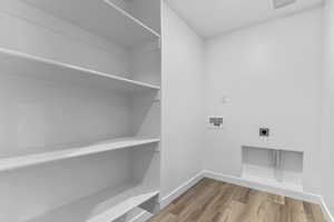 Laundry area with hookup for a washing machine, light wood-style floors, and hookup for an electric dryer