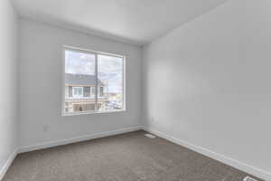 Carpeted spare room featuring baseboards