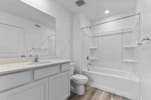 Full bath with light wood finished floors, shower / bathtub combination, and vanity