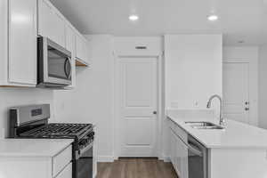 Kitchen featuring stainless steel appliances, a peninsula, light stone countertops, dark wood-style flooring, and recessed lighting