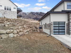 View of home's exterior with a mountain view, stone siding, a garage, and a balcony