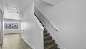 Stairs with wood finished floors and a textured ceiling