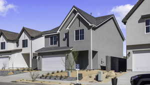 Traditional-style home featuring an attached garage, a tiled roof, stucco siding, and concrete driveway