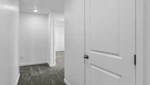 Corridor featuring dark carpet and recessed lighting
