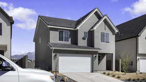 Traditional-style home with a garage, stucco siding, a mountain view, and driveway
