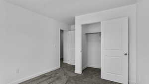 Unfurnished bedroom with dark colored carpet and a closet
