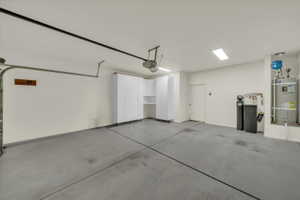 Garage featuring strapped water heater and a garage door opener