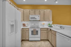 Kitchen featuring light wood finish cabinets, white appliances, and light countertops