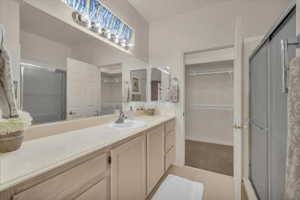 Full bath with a spacious closet, a stall shower, and vanity