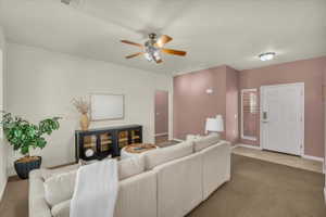 Carpeted living area with ceiling fan, track lighting, and a textured ceiling