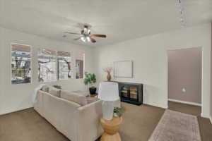 Carpeted living area featuring ceiling fan and rail lighting