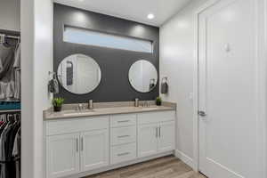 Bathroom featuring a spacious closet, double vanity, light wood finished floors, and recessed lighting