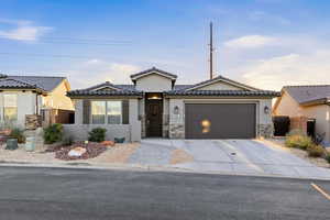 View of front of property featuring stucco siding, a tile roof, driveway, and stone siding