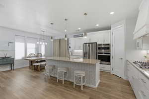 Kitchen featuring white cabinets, a kitchen bar, stainless steel appliances, and hanging light fixtures