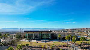 Back of house with stucco siding, a mountain view, a patio, a yard, and stone siding
