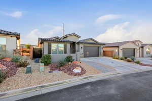 View of front of home with driveway, stucco siding, an attached garage, a tiled roof, and stone siding