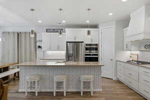 Kitchen featuring white cabinetry, stainless steel appliances, pendant lighting, light wood-style floors, and open shelves