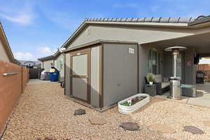 View of side of property with a fenced backyard, a tiled roof, and a storage unit