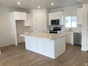 Kitchen featuring white cabinets, stainless steel appliances, a center island, dark wood-style flooring, and recessed lighting