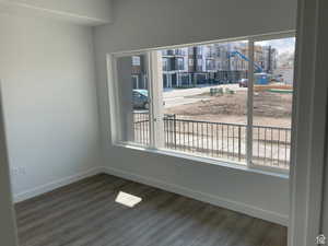 Spare room with baseboards and dark wood-type flooring
